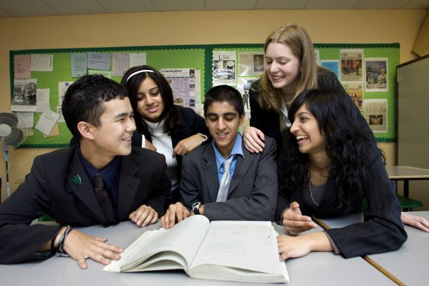 Children and teachers discussing a notebook.