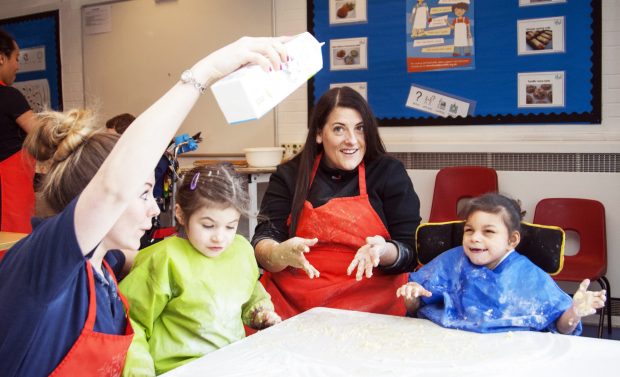 Two children with staff in a classroom doing messy play.
