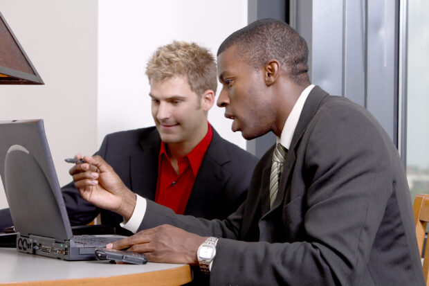 Two men looking at a laptop screen.