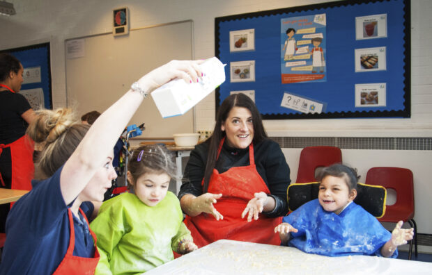 Children in a classroom with two staff members