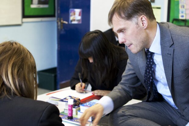 Teacher helps two pupils with their work.