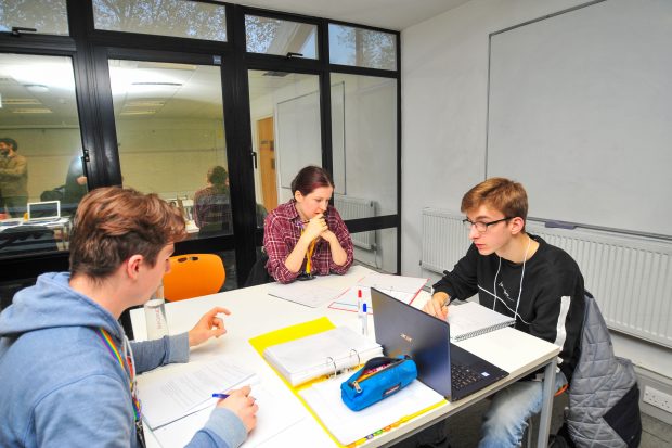 Teenage students sitting around a desk