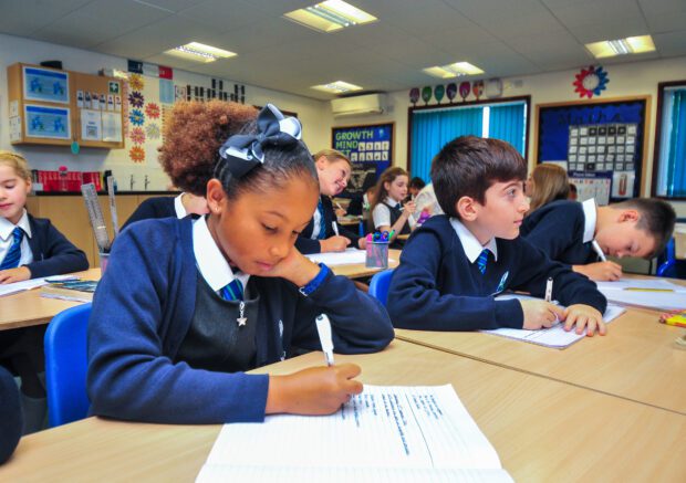 Primary-age pupils working at desks in a classroom