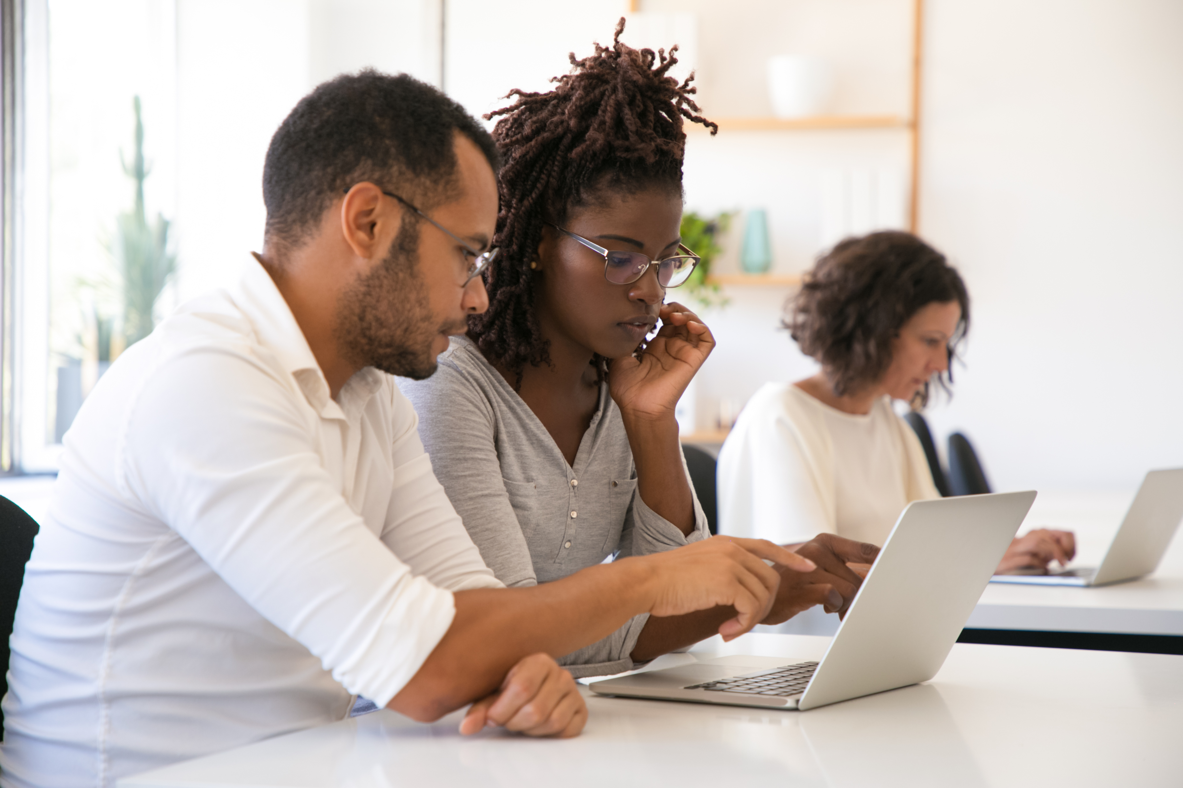 Two adults are working together, looking at a laptop