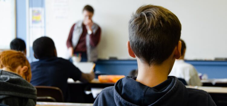 A class of students facing a teacher at a whiteboard