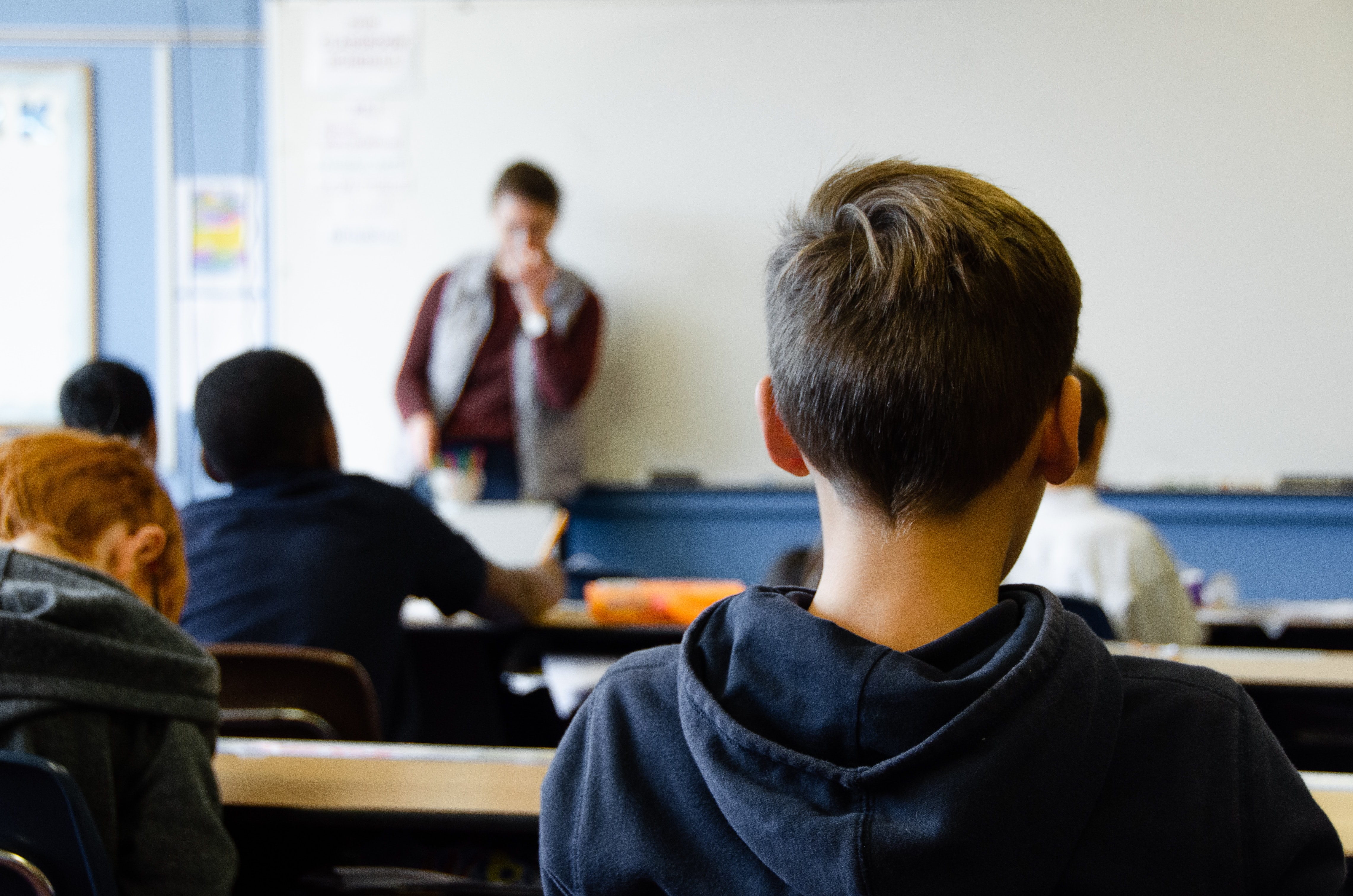 A class of students facing a teacher at a whiteboard